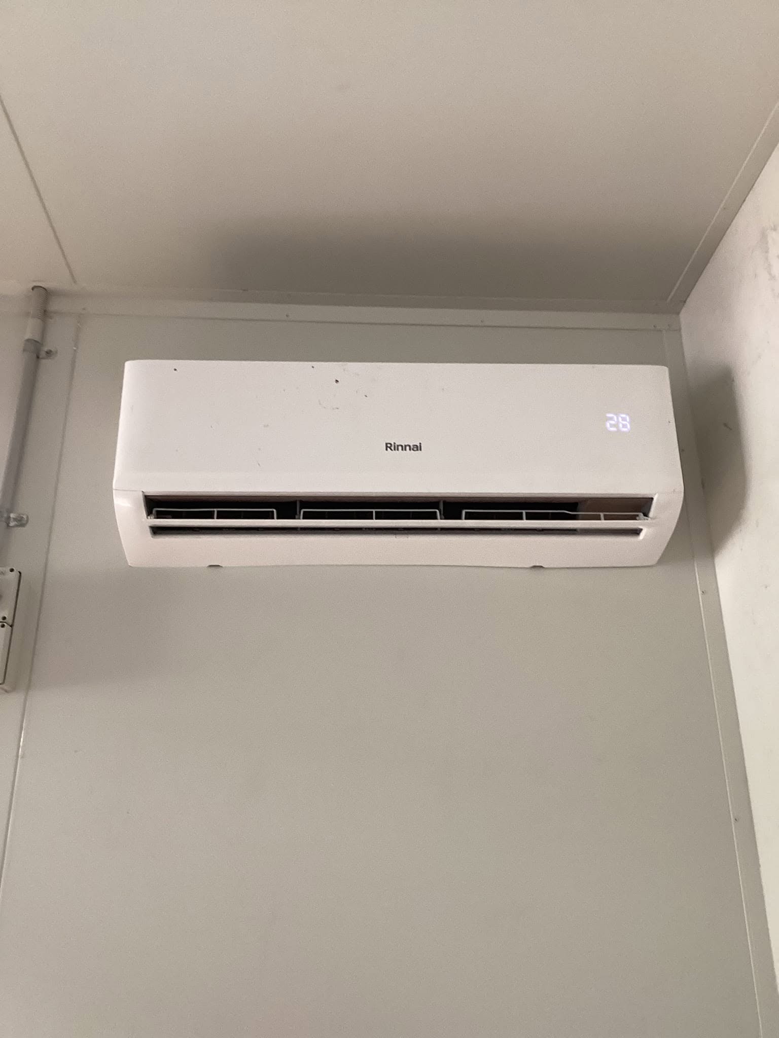 Rinnai split-system air conditioning indoor unit mounted on a ceiling corner