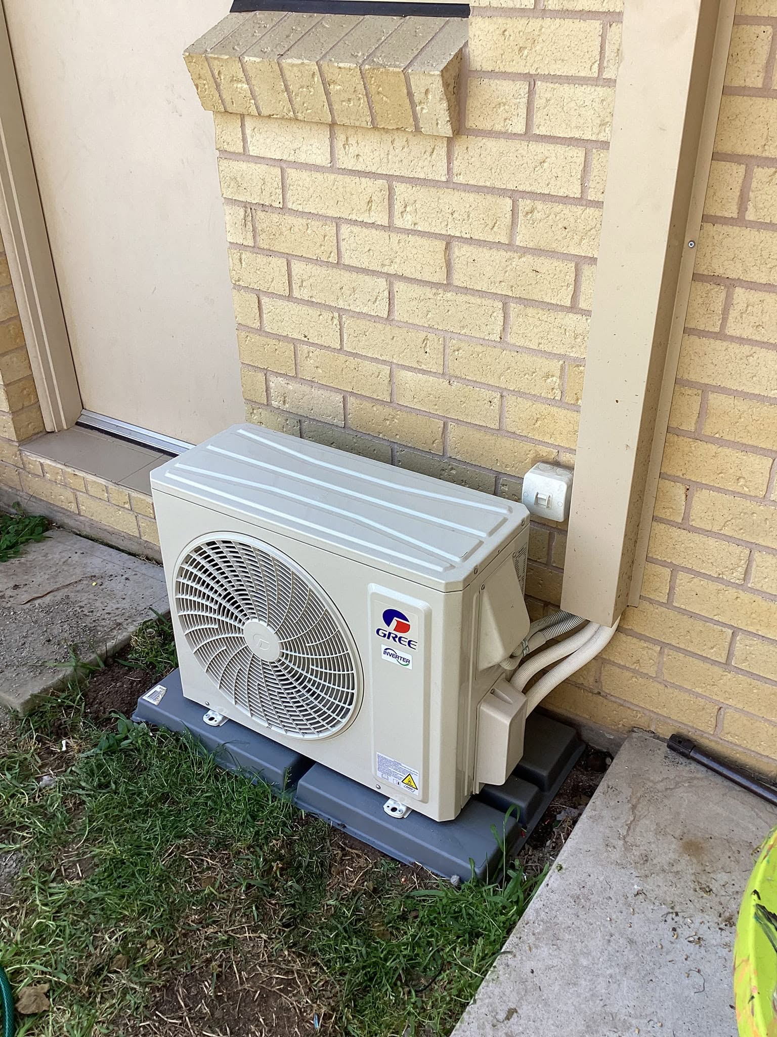 Gree split-system air conditioning outdoor unit installed on a brick pier